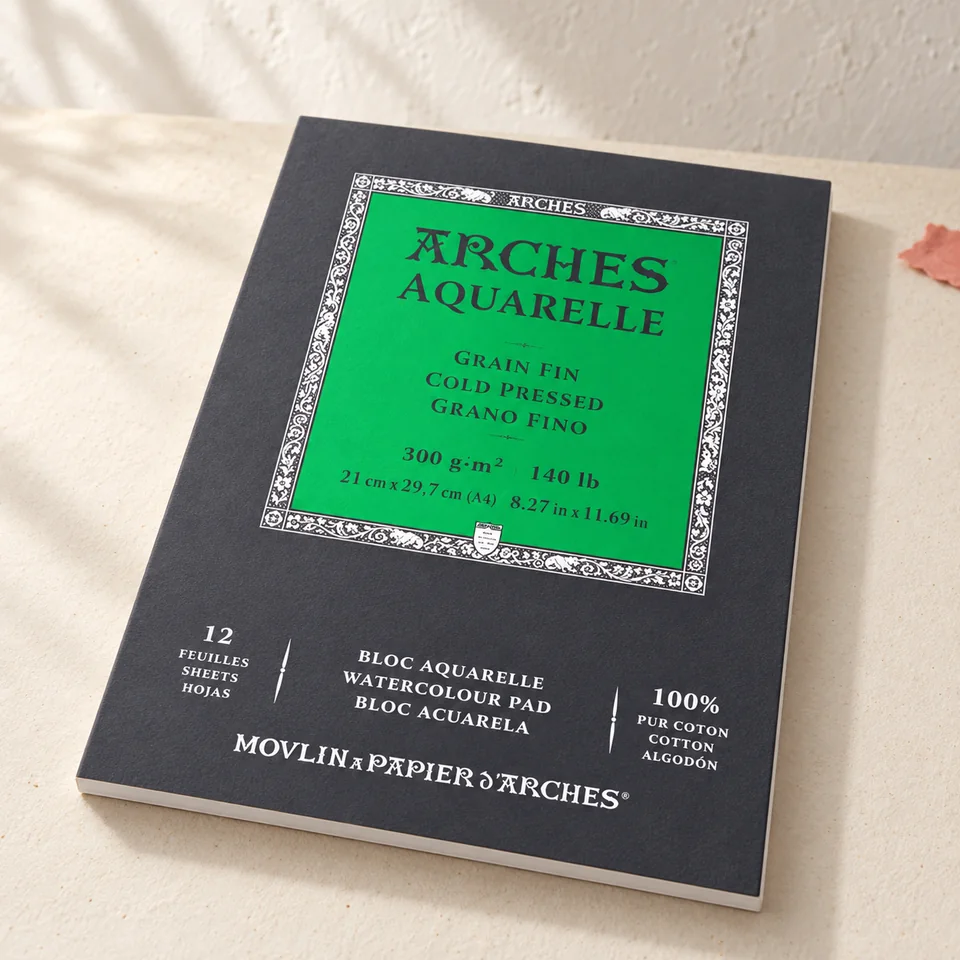 Arches — aquarelle 300 g à grain fin de Arches, mise en situation dans un atelier de papier écru et corail