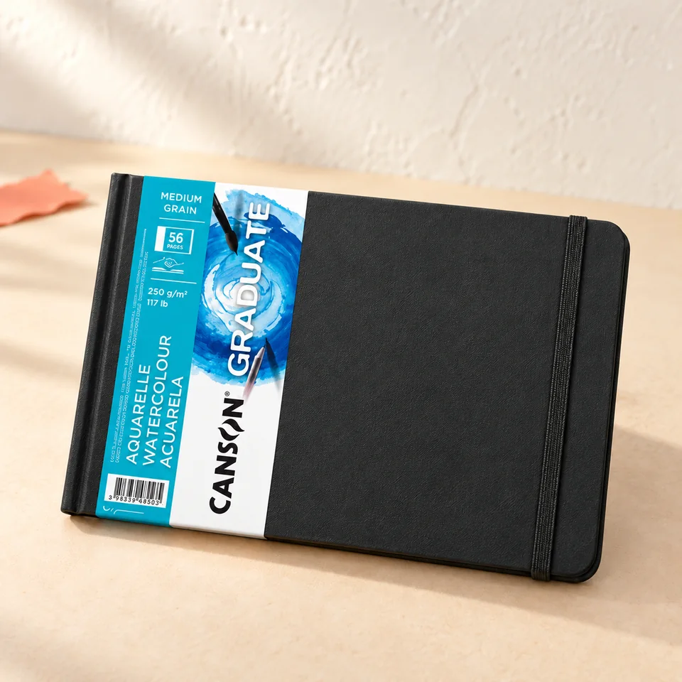 Canson — Graduate Book aquarelle cousu de Canson, mise en situation dans un atelier de papier écru et corail