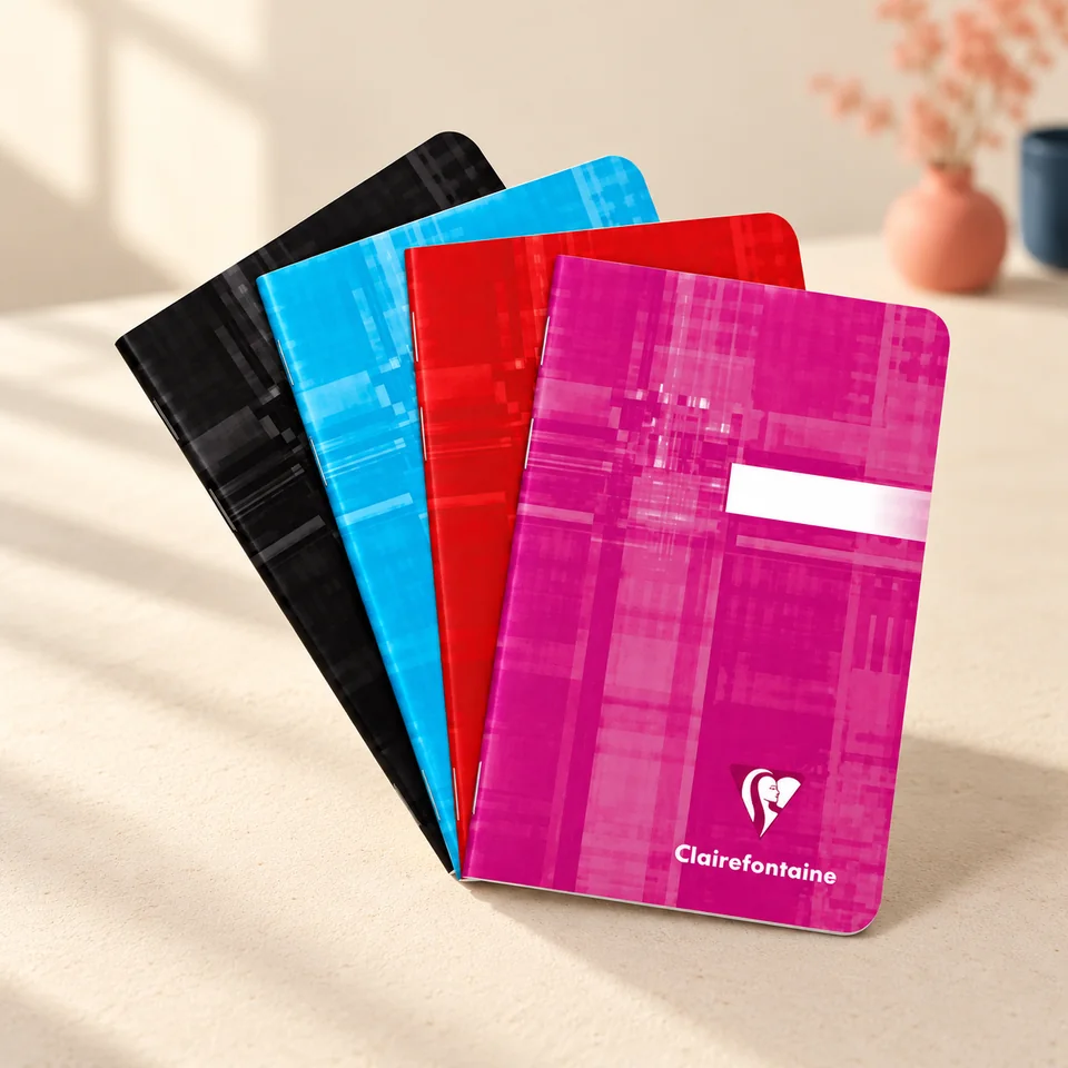 Clairefontaine — quatre carnets de poche agrafés de Clairefontaine, mise en situation dans un atelier de papier écru et corail